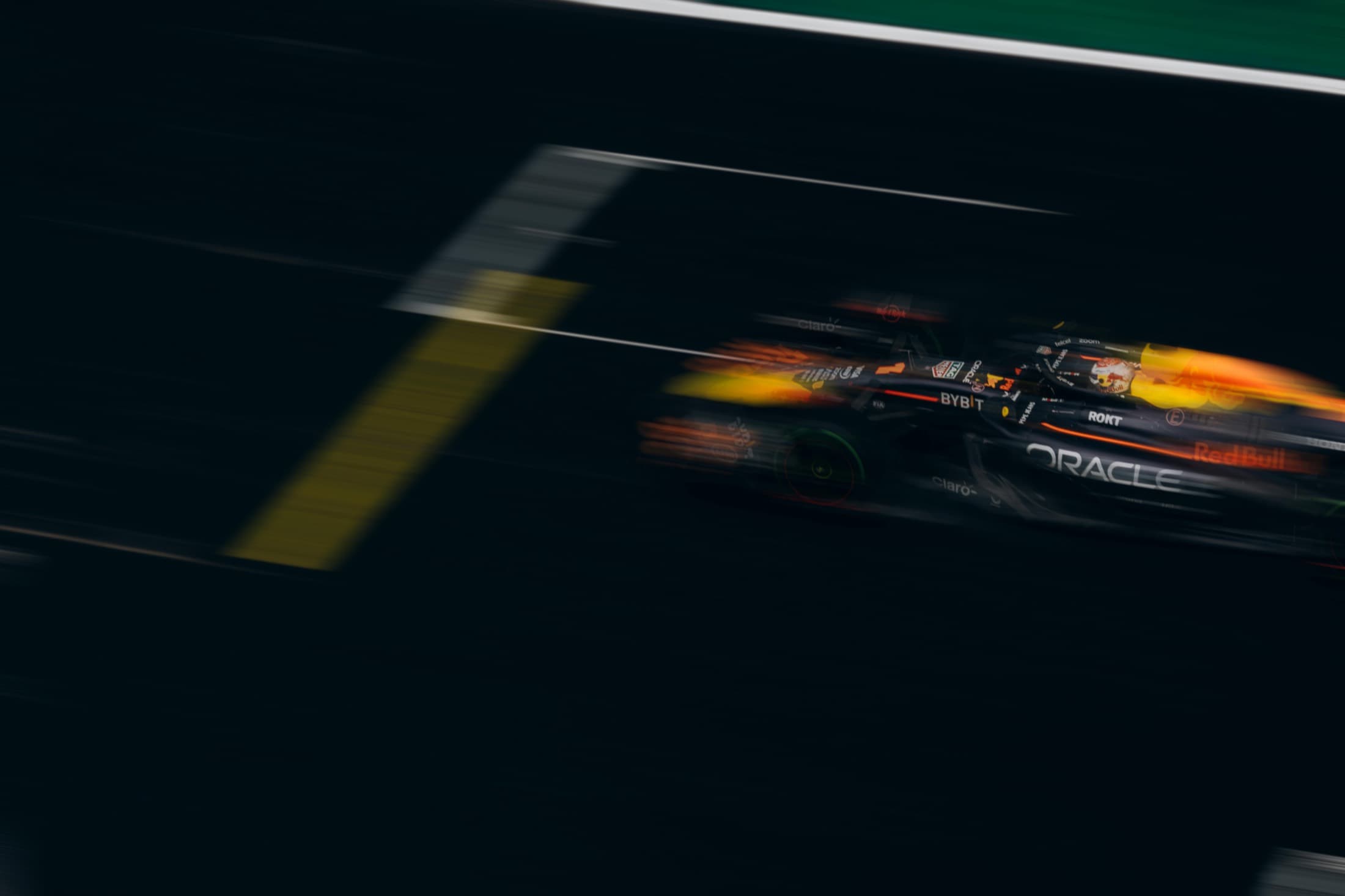 A Formula 1 car streaks through low light, headlights blurred with speed